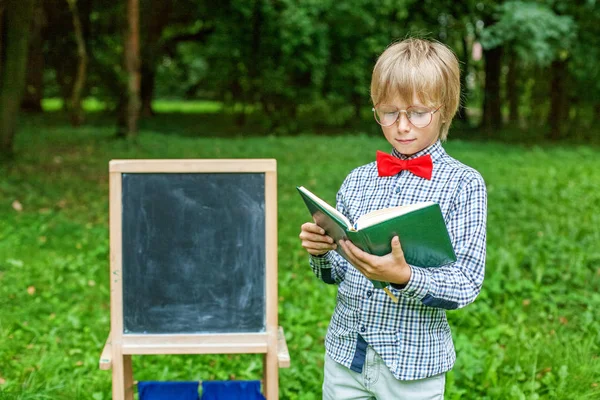 Niño rubio con estilo con gafas con un cuaderno . —  Fotos de Stock