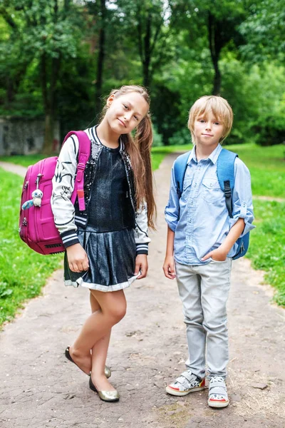 Der Junge und das Mädchen gehen mit Rucksäcken zur Schule. Schüler. — Stockfoto