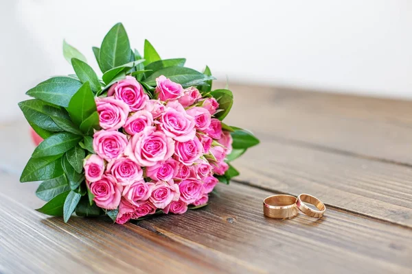 婚礼花束玫瑰和结婚戒指在一个木桌上。有限公司 — 图库照片