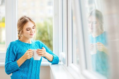 Genç kız sütlü kahve içer ve yansıtır. 