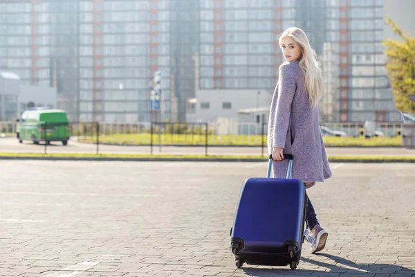 Fiatal nő egy bőröndöt, kimegy az utcára. — Stock Fotó