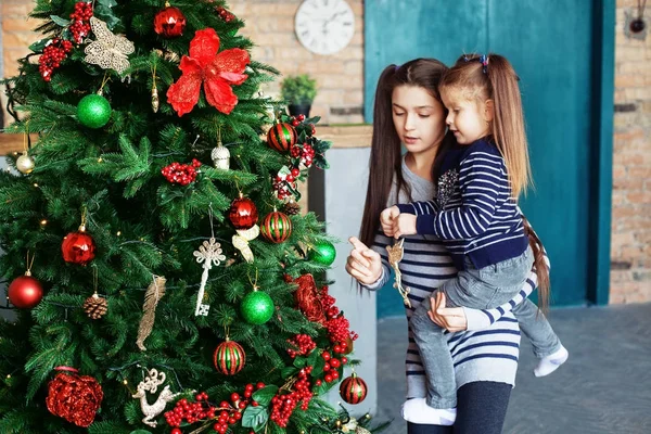 Hermana mayor decoró el árbol de Navidad con un poco de . — Foto de Stock