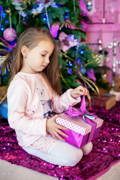 小さな女の子は、贈り物を開きます。クリスマスのコンセプト — ストック写真