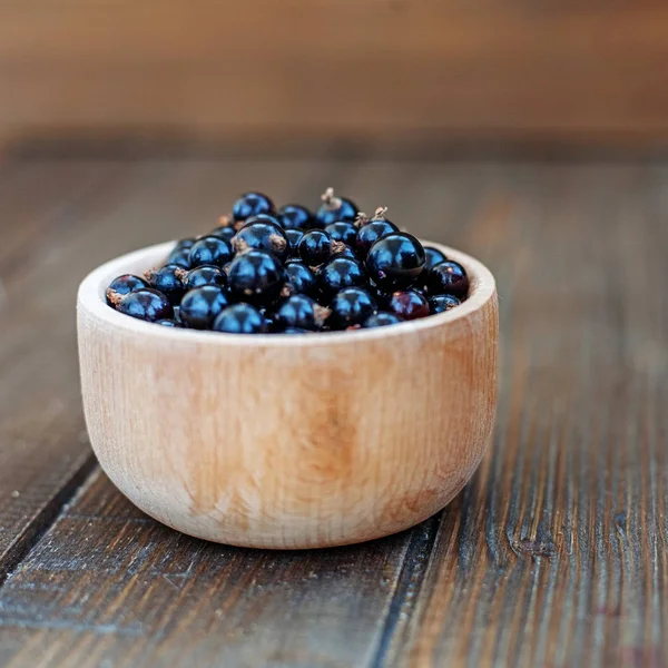 Useful berry. Black currants in a wooden bowl. Square. — Stock Photo, Image