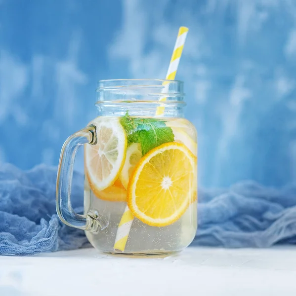 Refreshing fruit water in a glass jar. Lemon, orange and mint.