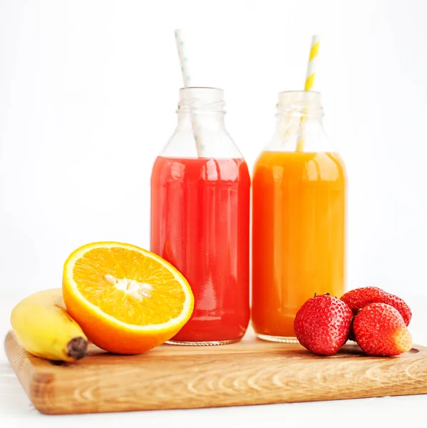 Fruit juice in bottles. Banana, orange and strawberries. — Stock Photo, Image