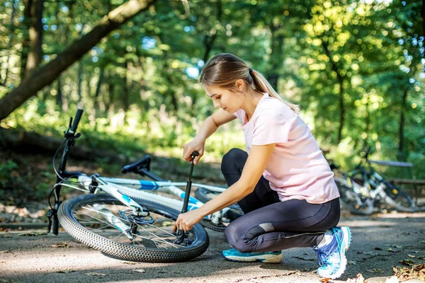 A woman repairs wheel of a bicycle. The concept of cycling — Stock Photo, Image