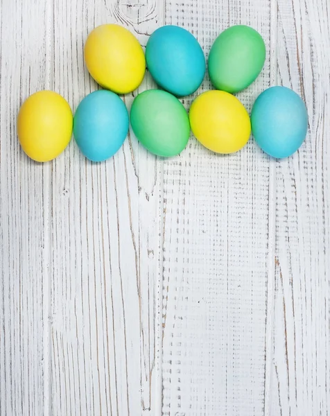 Vit trä bakgrund med färgade ägg för hälsning. — Stockfoto