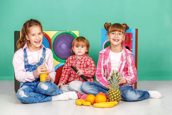 Three children watch tv and eat fruits.