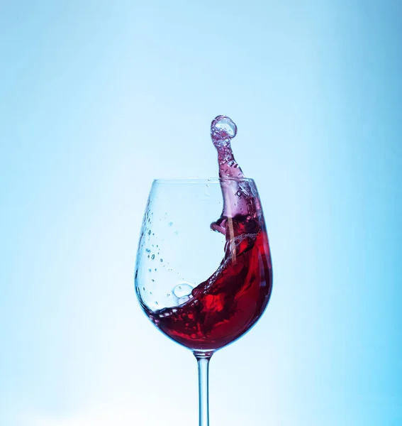 Delicioso vino tinto en una copa sobre un fondo azul. El concepto — Foto de Stock