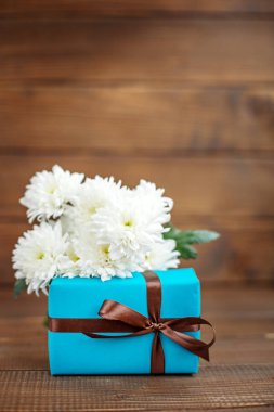 Kutlama için hediye ve beyaz çiçekli ahşap arka plan