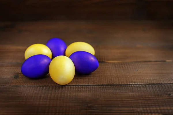 Yellow and purple Easter eggs on a wooden table. The concept of — Stock Photo, Image