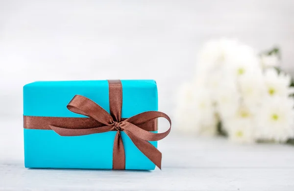 Blaue Schachtel mit einem Geschenk und Blumen. das Konzept des Muttertags, b — Stockfoto