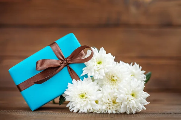 Holz Hintergrund mit einem Geschenk und Blumen Chrysanthemen. die co — Stockfoto