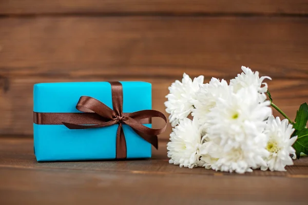 Holz Hintergrund mit einem Geschenk und Blumen für Glückwünsche. Nein. — Stockfoto