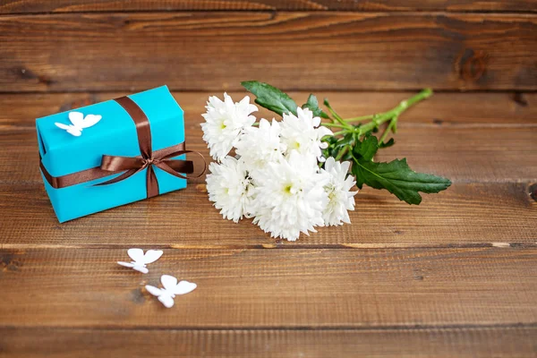 Holzhintergrund mit einem Geschenk und Blumen und Schmetterlingen. top v — Stockfoto