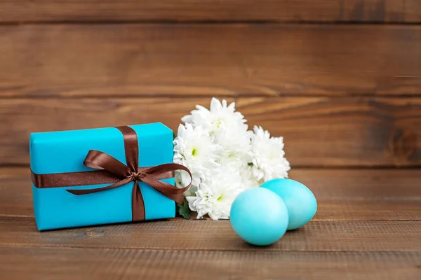 Eier und Blumen auf Holzgrund. Geschenk. Platz für Inschriften — Stockfoto