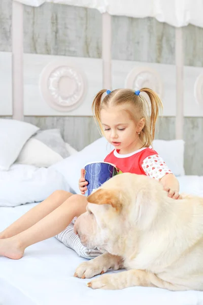 Malé dítě jíst popcorn. Pes leží poblíž dívka. — Stock fotografie