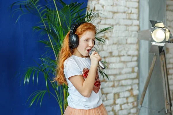Рыжая маленькая девочка поет песню в микрофоне. The conce — стоковое фото