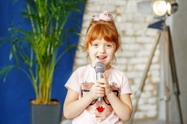 Маленькая рудная девочка поет под микрофон. Концепция chil — стоковое фото
