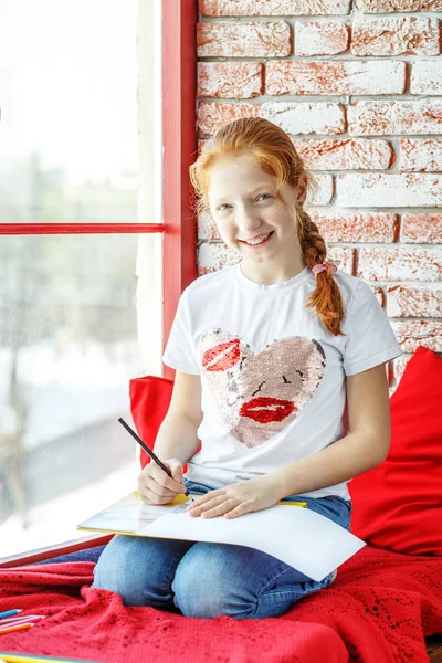 A beautiful kid sits on the windowsill and paints and laughs. Th — Stock Photo, Image