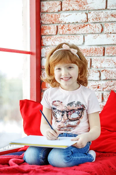 一个小孩坐在窗台上画画和大笑。的 — 图库照片