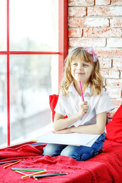 Ein kleines Mädchen sitzt auf der Fensterbank und denkt nach. Konzeption — Stockfoto