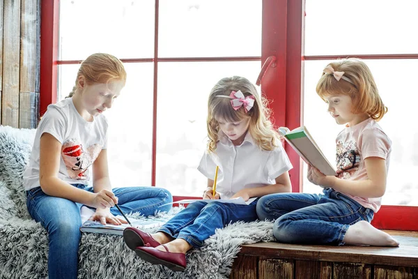 Drie kinderen lezen, tekenen en schrijven. Een groep kinderen is stoeterij — Stockfoto