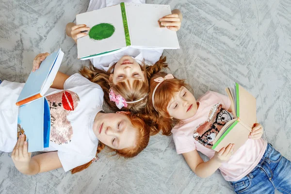 Um grupo de crianças deita-se no chão e lê livros. A concha — Fotografia de Stock