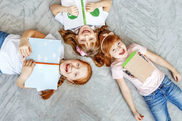 Троє щасливих дітей лежать на підлозі і читають книжки. Концепція — стокове фото