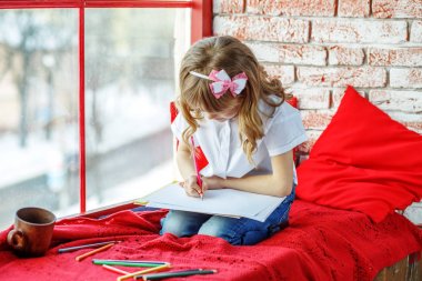 Küçük bir çocuk yazıyor ve pencere pervazına üzerinde oturur. Gebe chi