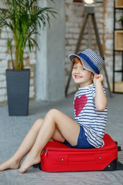 Kis gyerek, nevetett, és ül egy piros táska-egy kalap. Konc — Stock Fotó