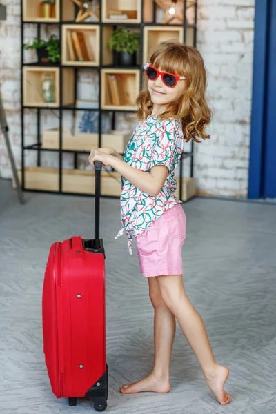 Kis gyerek napszemüveg piros bőrönddel. A koncepció, életmód — Stock Fotó