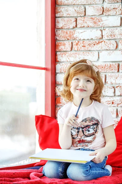 Denkt und zeichnet ein schönes Kind. das Mädchen sitzt auf dem Gewinn — Stockfoto