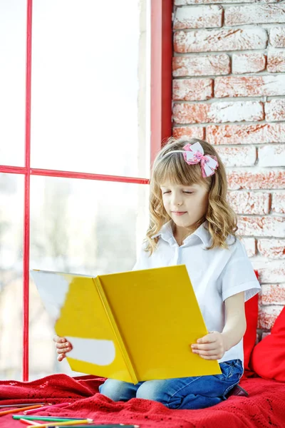 Een prachtig kind leest een boek in de buurt van het venster. Ontwerp childhoo — Stockfoto