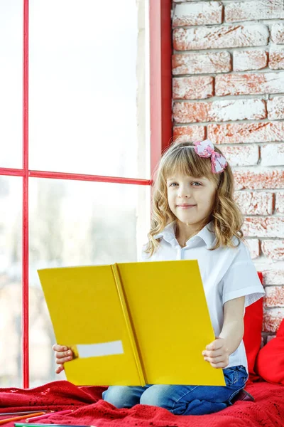 A happy child reads a book near the window. Conception childhood — Stock Photo, Image