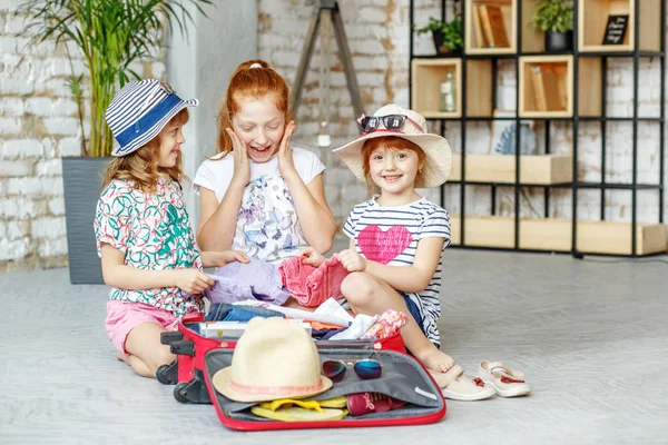Gelukkige kinderen pakken dingen in een koffer op een reis. Concept t — Stockfoto
