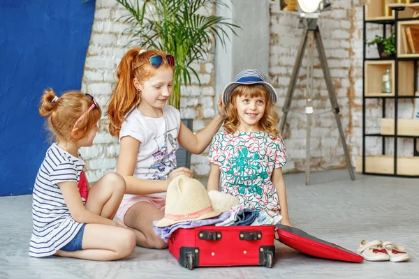 Трое веселых детей собирают чемодан для пляжного отдыха. Концепция , — стоковое фото