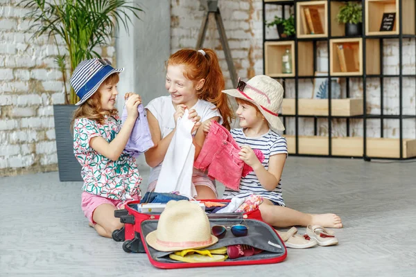 Three happy kids of girls pack a suitcase on a trip. Concept tou — Stock Photo, Image