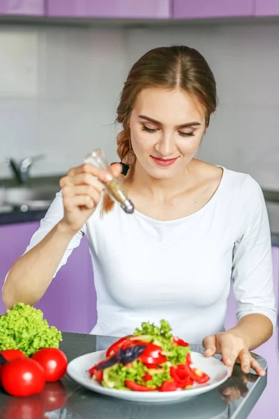 Une jeune femme ajoute des épices à une salade. Végétarien. Le concept est — Photo