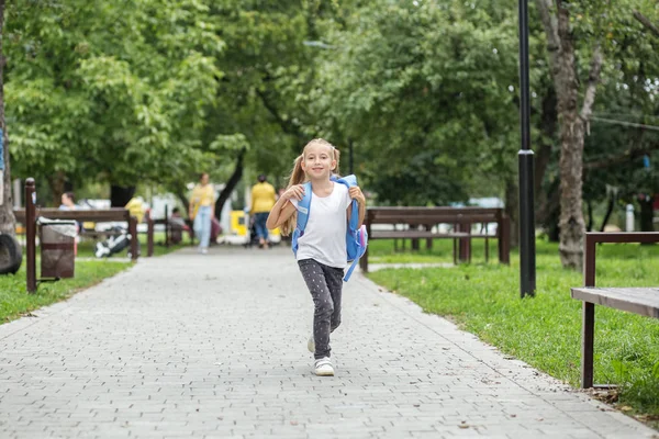 Barnflicka går från skolan med en ryggsäck. Begreppet skola, studier, utbildning, vänskap. — Stockfoto