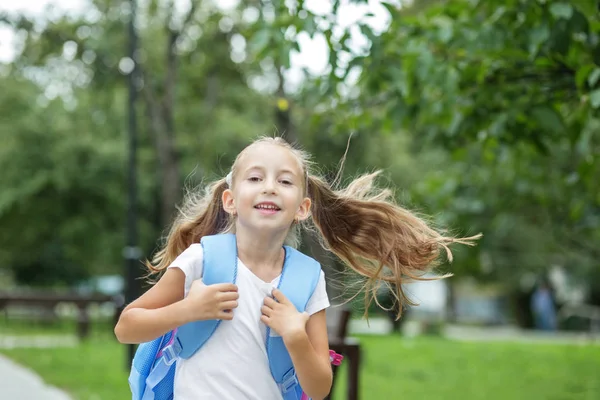 Kind meisje rent en glimlacht. Schoolmeisje met rugzak. De concep — Stockfoto