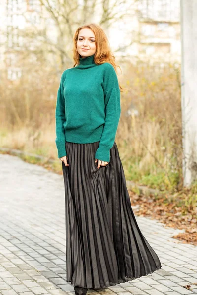 Hermosa mujer con una falda plisada y un suéter verde. El concepto de estilo y moda, estilo de vida . — Foto de Stock