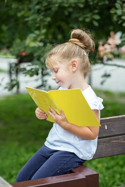 Маленькая умная девочка читает интересную книгу. Концепция вернулась в школу и воспитание . — стоковое фото