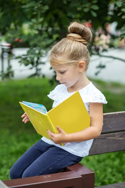 Uma criança pequena e inteligente está lendo um livro interessante. O conceito está de volta à escola e à educação . — Fotografia de Stock