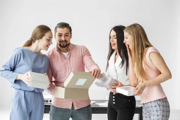 Kolleger på kontoret öppnar lådor med julklappar. En grupp anställda. Begreppet överraskningar och hemliga Santa. — Stockfoto