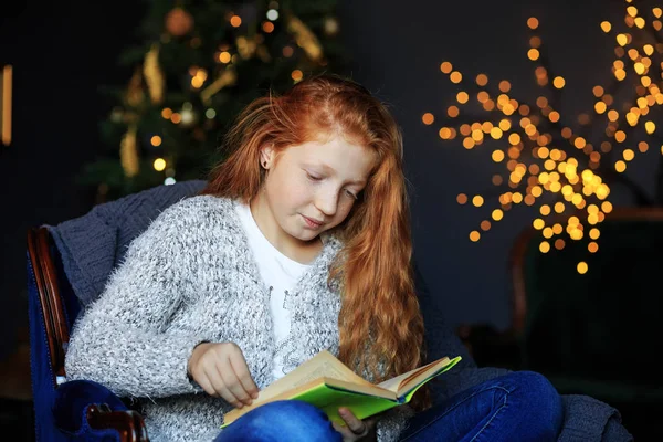 Tiener meisje leest een boek op kerstavond. Het begrip vakantie, vrolijk kerstfeest en kindertijd. — Stockfoto