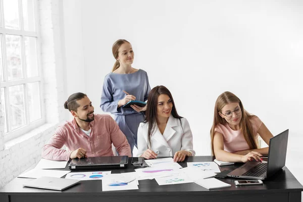 Un grupo de jóvenes colegas discuten tareas en la oficina. El concepto de emprendedores, éxito y trabajo . — Foto de Stock