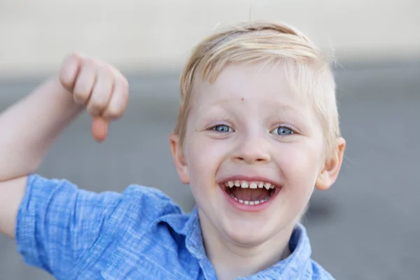 Ett litet starkt barn visar sina muskler och ler. Begreppet barndom, tillbaka till skolan och dagis. — Stockfoto