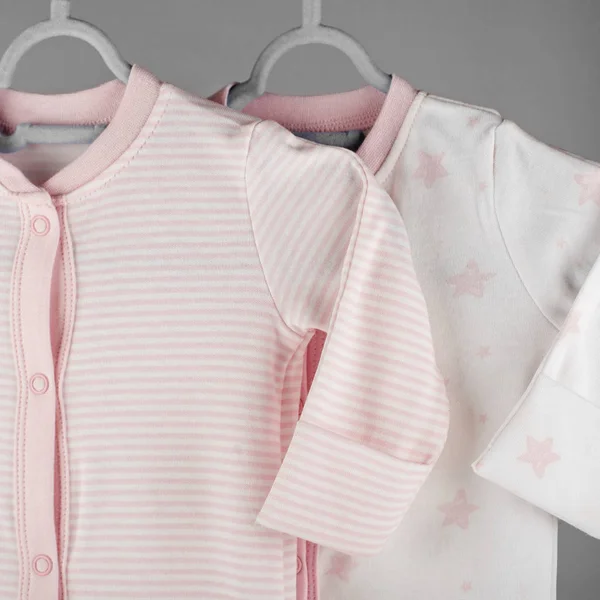 Pink striped clothes for a newborn hanging on a hanger. The concept of clothes, motherhood and newborn.